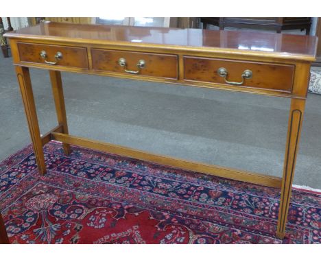 A yew wood three drawer console table 