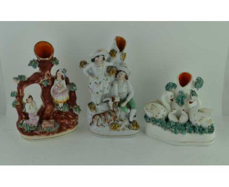 THREE 19TH CENTURY STAFFORDSHIRE POTTERY SPILL HOLDERS, one modelled as a family of swans beside a tree trunk, with shredded 