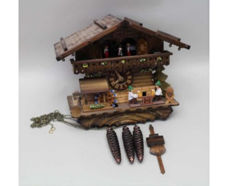 A SWISS CUCKOO CLOCK, of chalet form with various automation, having three cast metal pine cone weights Condition report: con