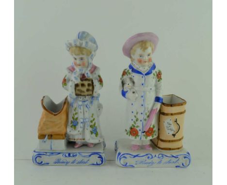 A PAIR OF LATE 19TH CENTURY CONTINENTAL CERAMIC VESTA HOLDERS, modelled as children with luggage, the bases inscribed "Ready 