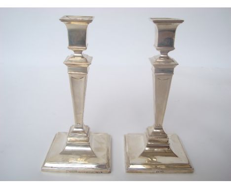 A pair of George V silver candlesticks, Sheffield, 1916 by Martin Hall & Co Ltd, with square urn form nozzles, on tapering sq