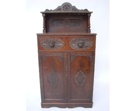 A carved mahogany chiffonier, the raised back with shaped pediment and shelf on turned supports, over a long drawer with mask