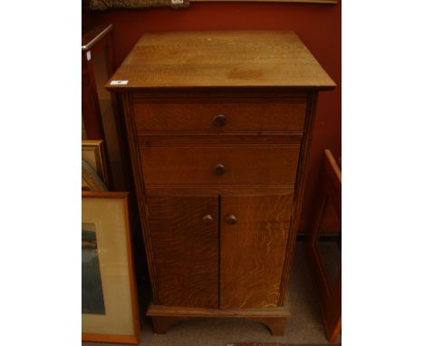 A light oak cabinet, with two short drawers above a pair of cupboard doors, on bracket feet. 