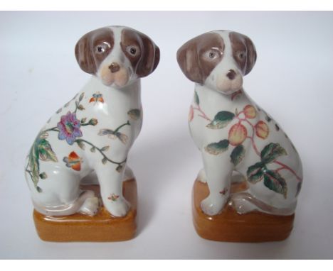 A pair of Chinese porcelain figures of seated dogs, on plinth, each decorated in colour enamel with flowering plants and inse