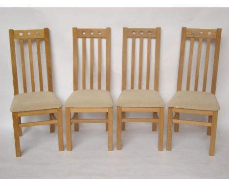A set of four modern light oak dining chairs with shaped slatted backs. 