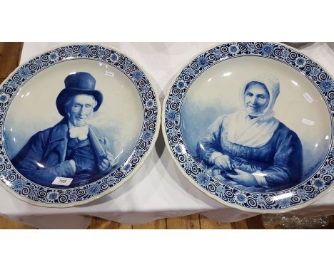 Pair Dutch delft pottery plaques painted with seated lady wearing bonnet, the other with gentleman smoking pipe, signed "Maas