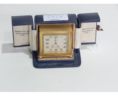 Zenith gilt metal cased travelling clock of angular form on bun feet mounted in blue leather case, retailed by Dibdin & Co Lt