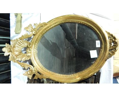Oval mirror with gilded frame and floral and shell decoration to the top 