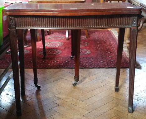 Mahogany fold-over top card table, serpentine edge, fluted frieze, on fluted tapering supports 