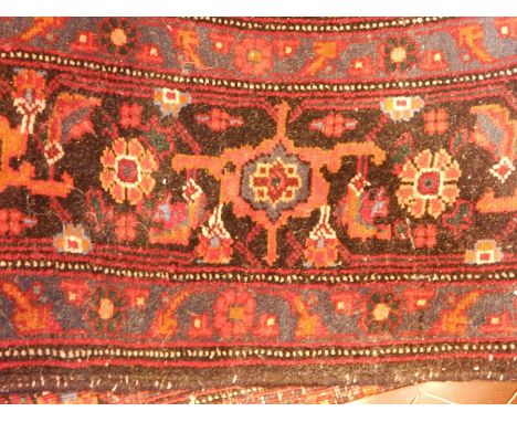 Persian style wool carpet, the red ground with central stepped medallion, geometric gul ground with stylised running floral b