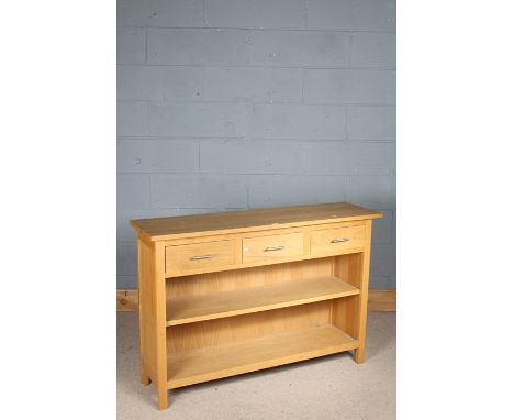 Light oak sideboard, the rectangular top with three frieze drawers, above an open shelf, raised on square legs, 124cm long, 8