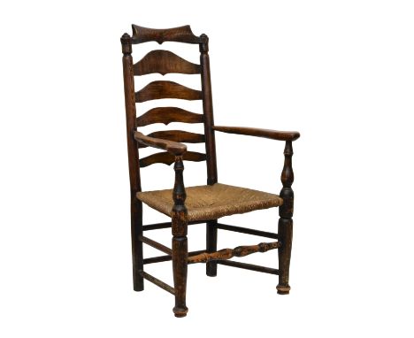 A George III stained beech and oak ladder back armchair, the shaped, scrolled top rail over a shaped ladder back, shaped arms