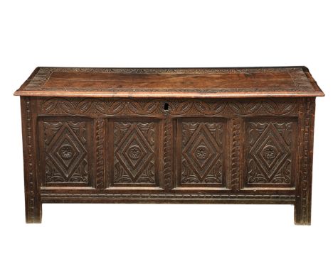A late 17th century four panel oak coffer, the two plank top with a carved border opening to a candle box with cover within a