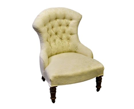 A Victorian button back nursing chair upholstered in ivory damask, raised on turned walnut front legs with pottery castors.  