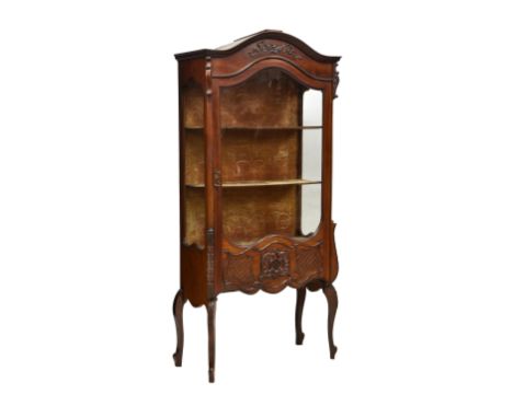 A Louis XV style mahogany display cabinet circa 1920, the flared arched top with floral swag carving over a single glazed doo