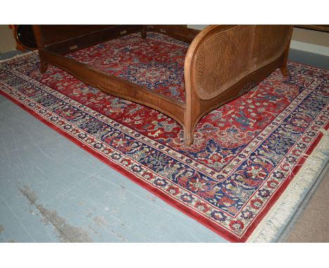 A machine-made Persian style carpet with hunting scenes, figures on horseback, central rosette and decorative border.