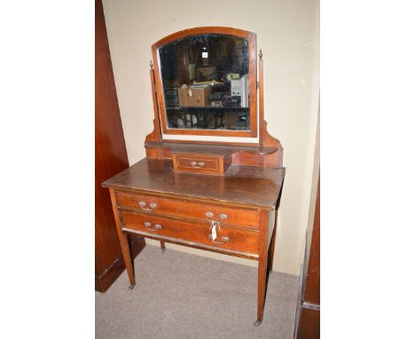 An Edwardian inlaid mahogany dressing table, the arched mirror back on tapering square supports above shaped shelf and centra