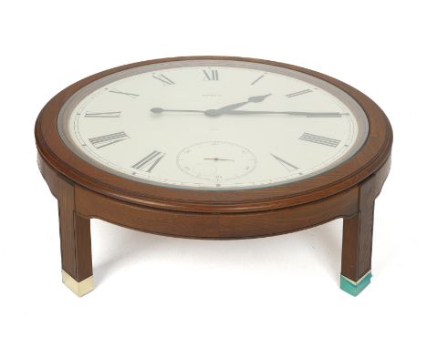 A HOWARD MILLER OAK CLOCK TABLE The circular glazed top inset with an oversized clock face with Roman numeral chapter ring an