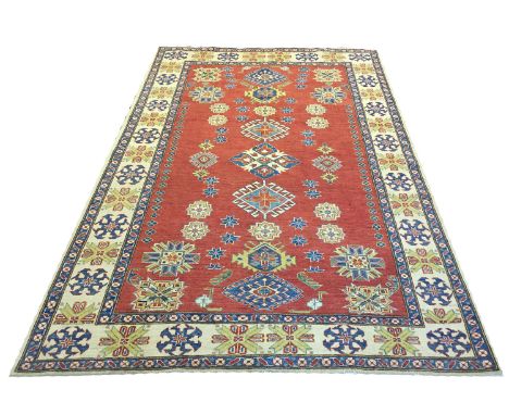 FINE KAZAK CARPET, 274cm x 173cm, scattered geometric medallions on a ruby field within multiple corresponding borders. 