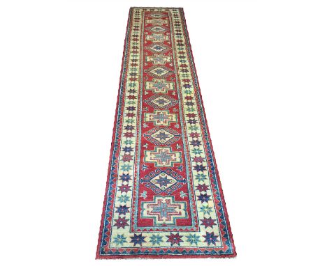 KAZAK RUNNER, 358cm x 80cm, multiple medallions on a ruby field.