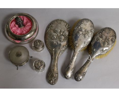 An Edwardian three piece silver brush and mirror set with Reynolds Angel decoration, a George V silver mounted glass powder b