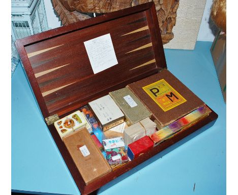 An early 20th century mahogany folding games board and contents to include; chessmen, playing cards etc 