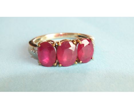 A ruby ring claw-set three oval rubies between diamond point-set shoulders, in 9ct gold mount, size O, 3.4g.