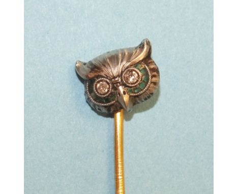 An Edwardian stick pin in the form of an owl's head, with diamond-set eyes, in white metal face set calibre-cut emeralds, 10m