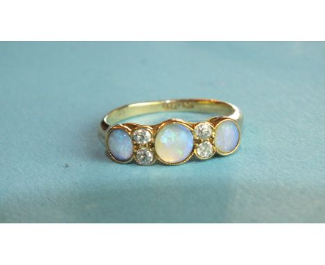 An opal and diamond ring millegrain-set three opals, with pairs of brilliant-cut diamonds between, in 18ct yellow gold mount,