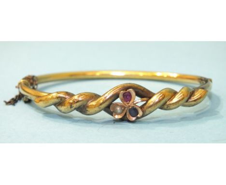 A Victorian yellow metal hinged bangle of twist design, set ruby, sapphire and pearl on a clover leaf motif, 57mm x 47mm insi