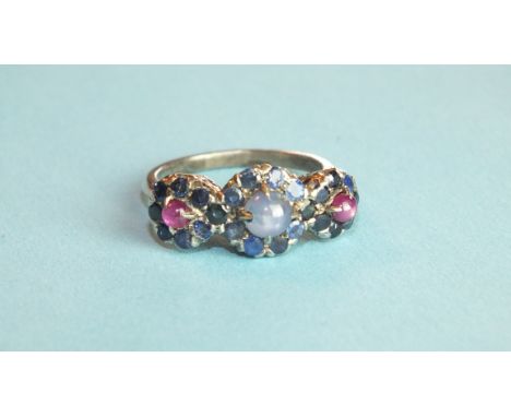 A sapphire and ruby ring set a cluster of a star sapphire cabochon within a surround of round-cut sapphires and between two s