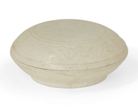 A Chinese white glazed porcelain circular box and cover, Yuan dynasty, the cover and base moulded with a band of scroll motif