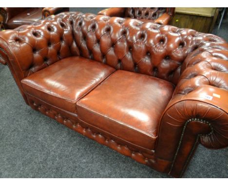 A modern red leather two-seater chesterfield sofa