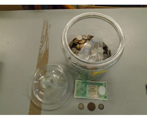 A large glass jar containing various coins from around the world to include a 1787 George III silver Shilling, an 1862 copper