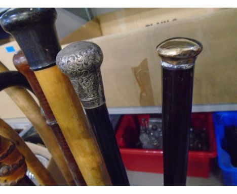 A brass stick stand with a quantity of umbrellas and walking canes to include one with a 9ct gold top, and another with a sil