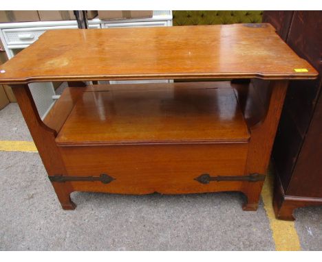 An Arts and Crafts oak monks bench with wrought iron brackets and a hinged bench seat