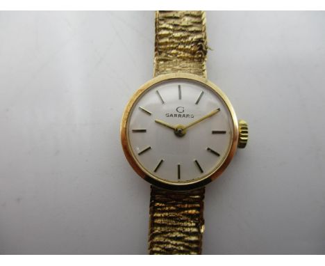 A Garrard 9ct ladies manual wind wristwatch having a silvered dial with baton markers, the integral strap hallmarked 375, wit