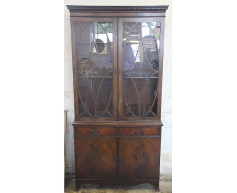 A Regency style mahogany bookcase cabinet, with moulded cornice above two oval astragal glazed doors, over two drawers and tw