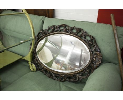 OVAL BEVELLED EDGE WALL MIRROR IN A CARVED AND PIERCED OAK FRAME OF FOLIATE SCROLL AND SHELL DESIGN 