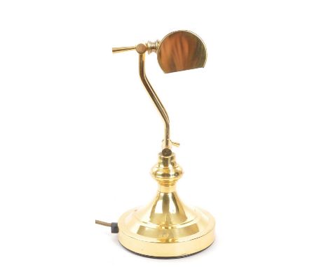 A 20th century brass bankers lamp. The lamp raised on a circular stepped pedestal base, having twin adjustable arms, and a cy