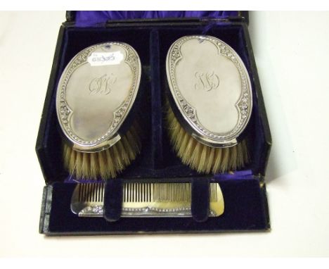 A pair of silver backed brushes, initialled, Chester 1920, and a matching comb, cased