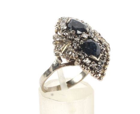 A sapphire and diamond 'shaped' cluster ring. Centred with two very-dark blue pear-shaped sapphires within a small eight-cut 