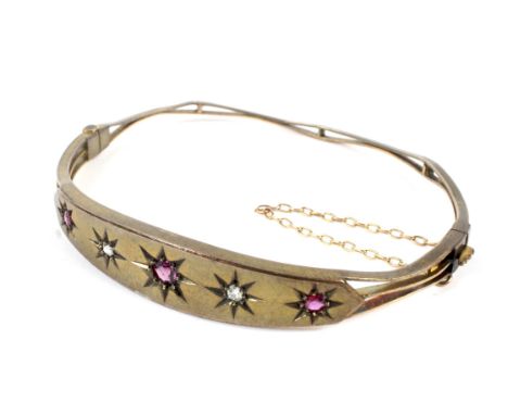 An early 20th century rose gold, ruby and diamond bangle. The front in the form of a slightly tapering panel star-gypsy set a