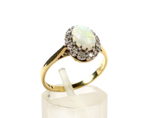 An 18ct gold, opal and diamond oval cluster ring. Centred with an oval cabochon white opal which displays a pleasing mostly g