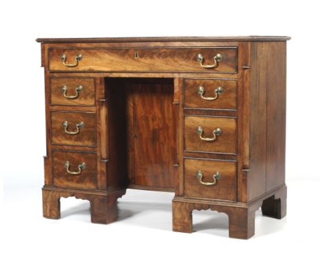 A 19th Century mahogany kneehole desk. The rectangular moulded top above a frieze drawer and a central cupboard flanked by tw