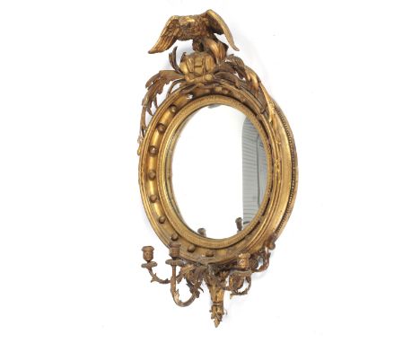 A 19th century Regency giltwood and gesso convex girondole mirror. The beaded frame surmounted with an eagle perched on rockw