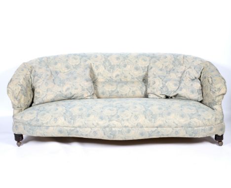 An Edwardian upholstered button back parlor sofa. With a low back rest, the seat of serpentine form, raised on turned frontal