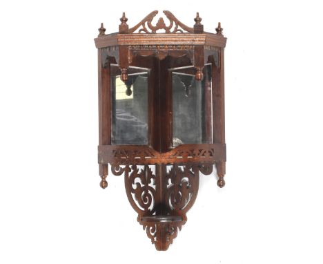 An Edwardian stained wooden hanging mirrored wall shelf. With a pierced foliate upper tier positioned over a mirrored lower g