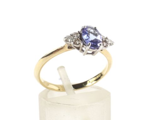 A modern 18ct gold, tanzanite and diamond dress ring. Centred with an oval mixed-cut tanzanite between small round brilliant 