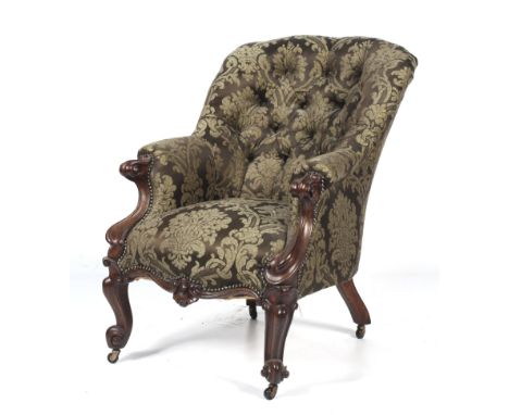 A Victorian oak framed button-back scroll armchair. With scrolled arms terminating in carved supports, mounted on carved cabr